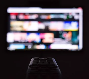 A streaming interface on a television, viewed past a remote control